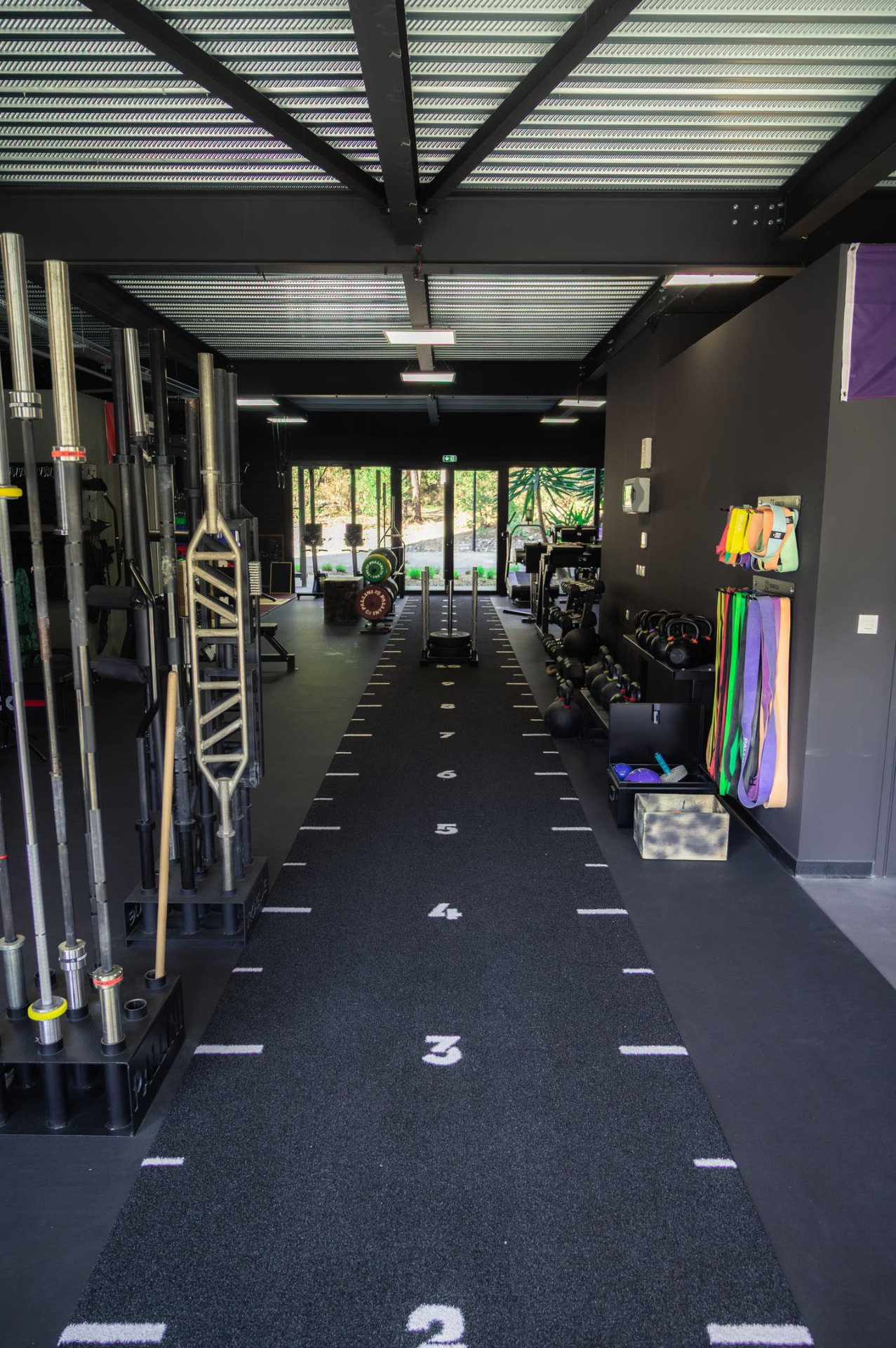 Vue d'ensemble de la salle Uruz avec piste de sprint et racks à barres